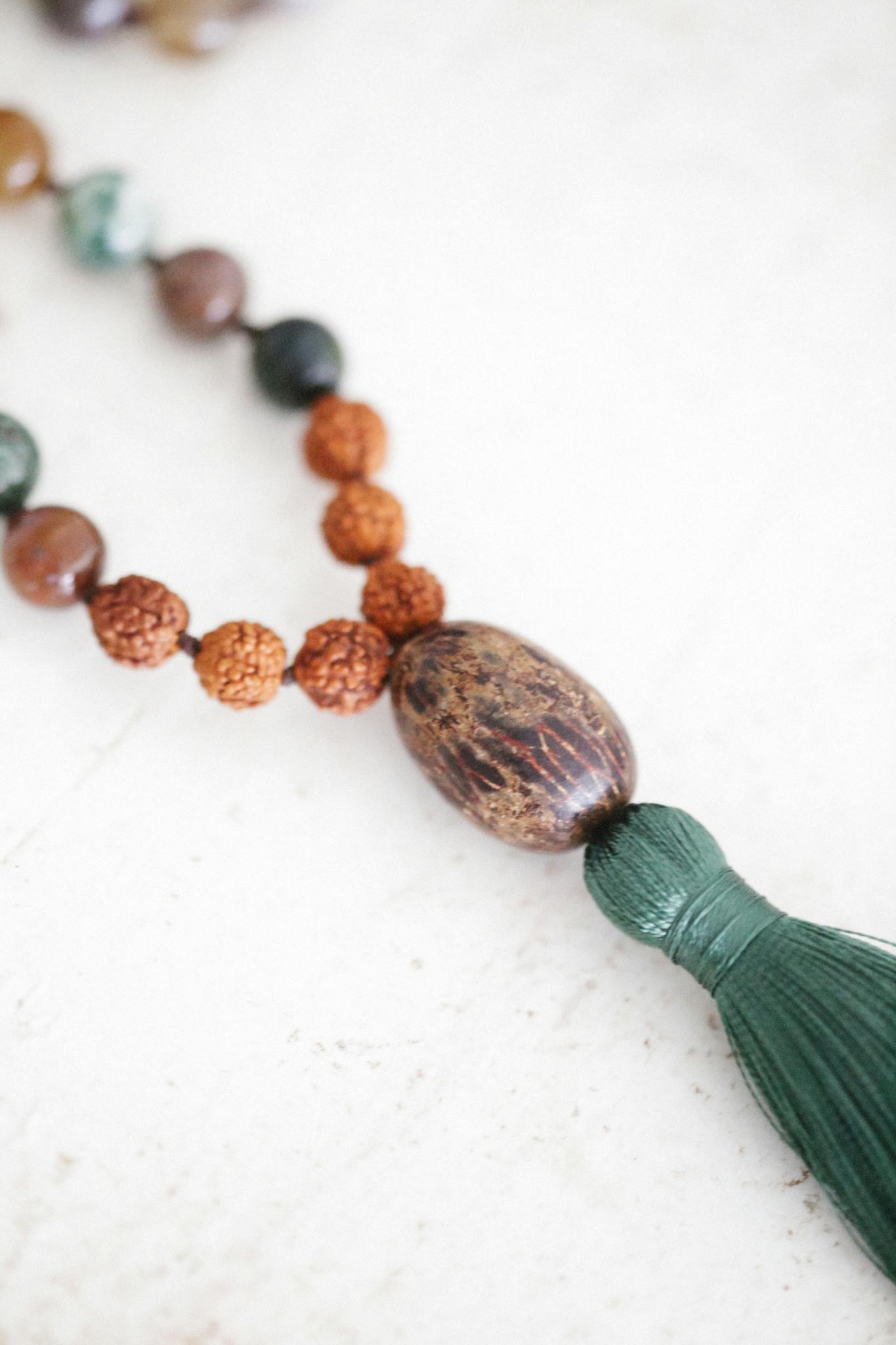 Close-up of a handcrafted beaded necklace with a tassel on a white background.
