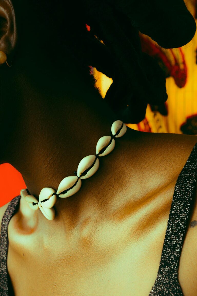 Close-up of a woman wearing a seashell necklace, featuring warm tones and a stylish design.